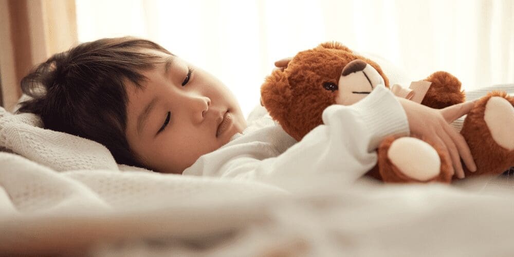 お気に入りのぬいぐるみを抱きしめて眠る子ども