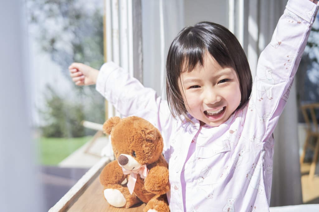 Morningroutinechildren2 | my stellaマイステラブログ|子どもの好きが育つヒントと親子の時間 朝日の中、スッキリと目覚める子どもとくまのぬいぐるみ。子どもが素敵な笑顔
