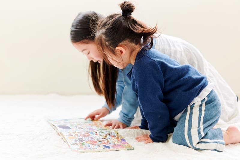 絵本の中から家族のキャラクターを指さして見つける子どもたち