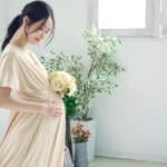花束を持ち微笑む妊婦さん｜出産祝いに贈りたい心温まるギフトのイメージ