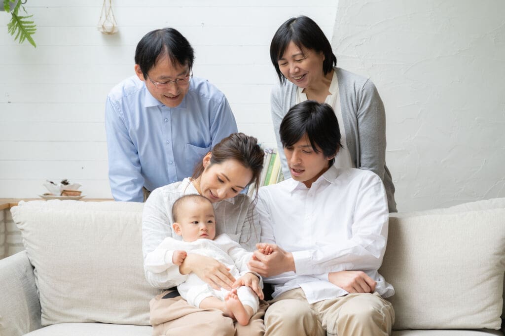両親と祖父母に囲まれて笑顔を向ける、1歳の赤ちゃん