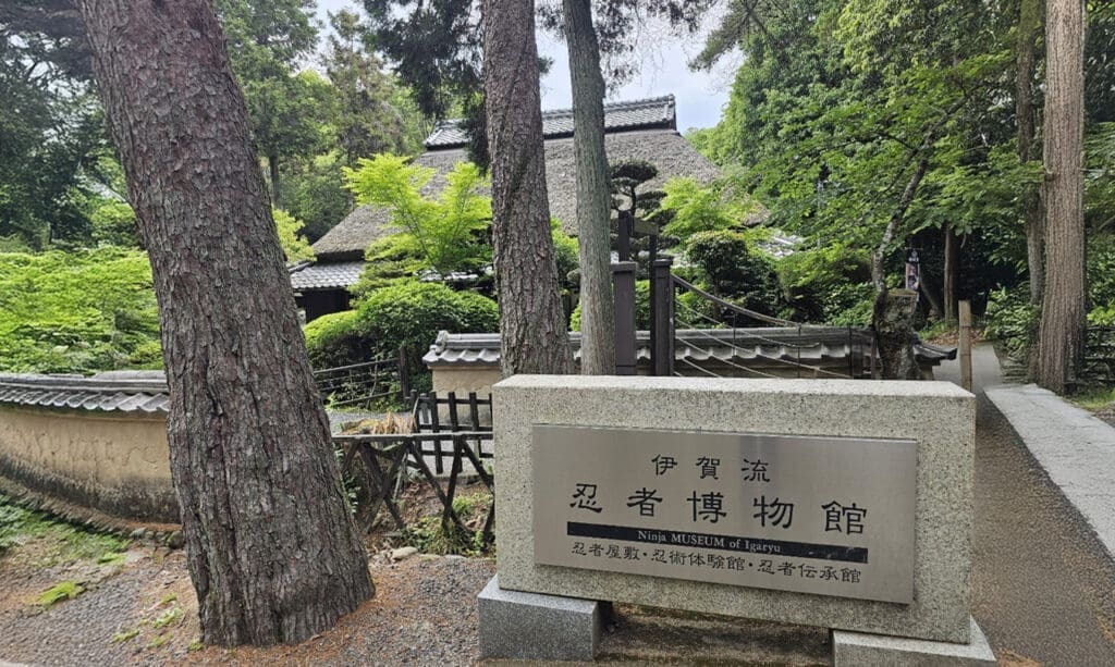 Iga-ryu-ninja-museum-entrance 三重県伊賀市にある伊賀流忍者博物館と、木々に囲まれた茅葺き屋根の建物外観